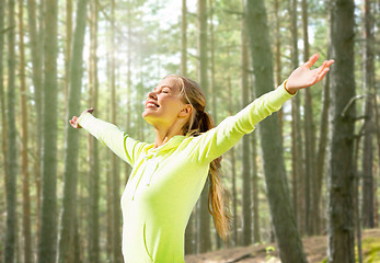 Image showing happy woman in sport clothes raising hands