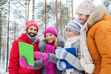 Image showing smiling friends with tablet pc in winter forest