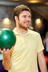 Image showing happy young man holding ball in bowling club