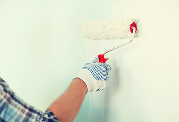 Image showing close up of male in gloves painting wall