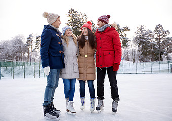 Image showing happy friends ice skating on rink outdoors