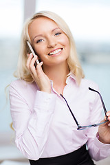 Image showing smiling businesswoman with smartphone in office