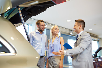 Image showing happy couple with car dealer in auto show or salon