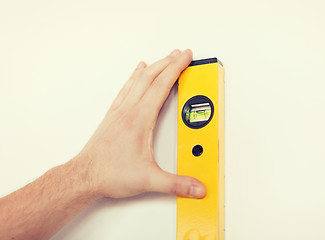 Image showing close up of male with spirit level mesuring wall