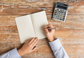 Image showing close up of hands with calculator and notebook