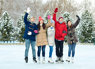 Image showing happy friends ice skating on rink outdoors