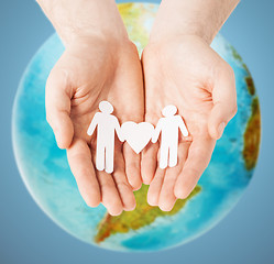 Image showing male hands with paper gay couple figures and globe