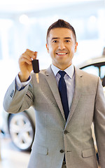 Image showing happy man showing key at auto show or car salon