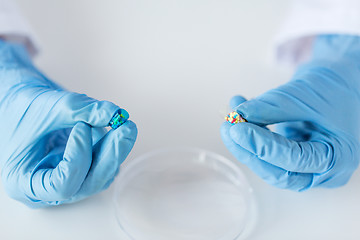 Image showing close up of scientist hands holding pill in lab