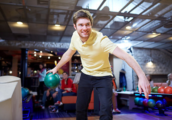 Image showing happy young man throwing ball in bowling club