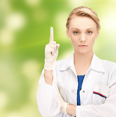 Image showing smiling young female doctor pointing her finger up