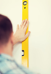 Image showing close up of male with spirit level mesuring wall