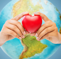 Image showing woman hands holding red heart over earth globe