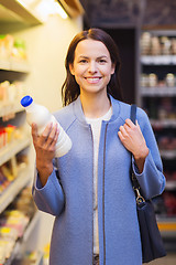 Image showing happy woman holding milk bottle in market