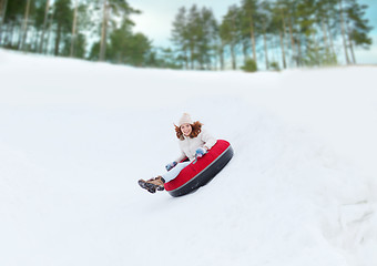 Image showing happy teenage girl sliding down on snow tube