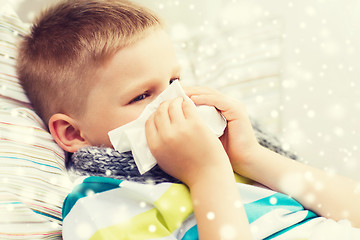 Image showing ill boy blowing nose with tissue at home