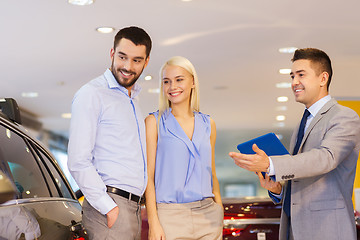 Image showing happy couple with car dealer in auto show or salon