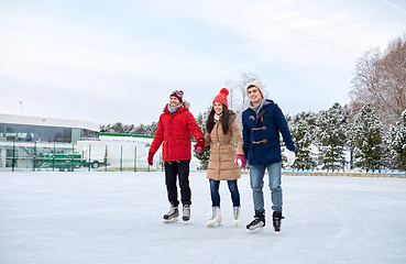 Image showing happy friends ice skating on rink outdoors