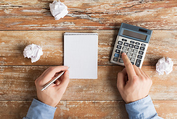 Image showing close up of hands with calculator and notebook