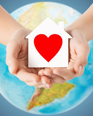 Image showing human hands holding paper house with red heart