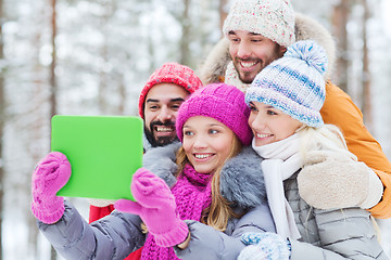 Image showing smiling friends with tablet pc in winter forest