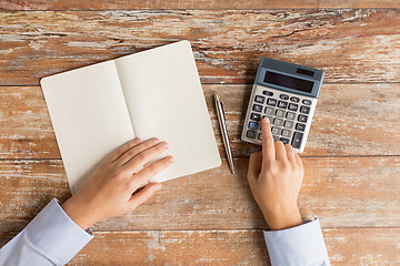 Image showing close up of hands with calculator and notebook