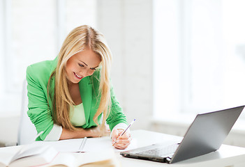 Image showing smiling student girl writing in notebook