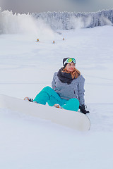 Image showing Young girl Oversized sitting with your snowboard in the snow