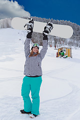 Image showing Young chubby woman in winner attitude, raises your snowboard in the air.