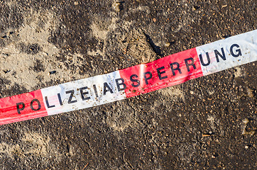 Image showing German police line red white tape on street asphalt dirt