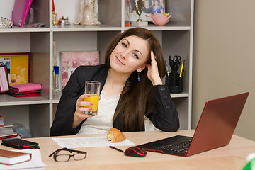 Image showing The girl at the desk holding a glass of juice