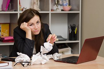 Image showing Sad girl in the office with a bunch of crumpled paper