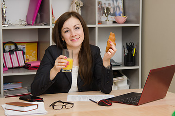 Image showing The girl at the desk with a meal