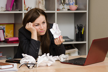 Image showing Sad girl in the office holds a crumpled sheet of paper