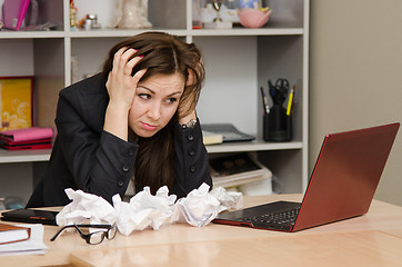 Image showing The girl at computer with a bunch of crumpled sheets paper