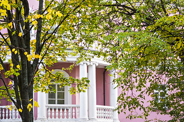 Image showing White balcony of pink house of classic style in autumn garden 