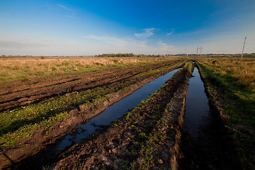 Image showing Field with a road rut full of water
