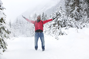 Image showing Happy young man with snow glasses throws up snow