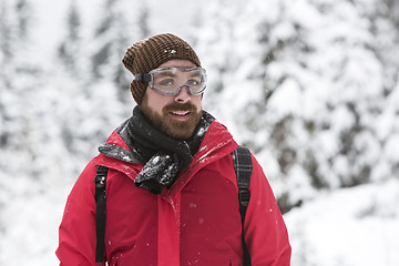 Image showing Young man with snow glasses smiles into the camera