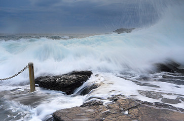 Image showing Bracing as powerful waves come crashing over rocks