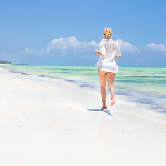 Image showing Woman running on the beach in white shirt. 