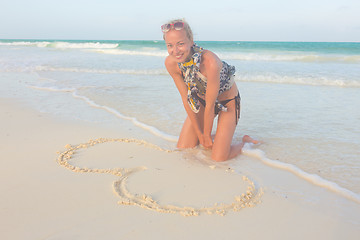 Image showing Woman drawing heart on the sand.