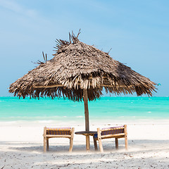 Image showing Two deck chairs and umbrella on tropical beach.