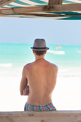 Image showing Hipster man with hat on tropical sandy beach.