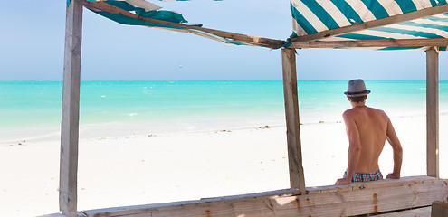 Image showing Hipster man with hat on tropical sandy beach.