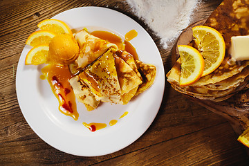 Image showing stuffed pancakes with orange syrup and ice-cream