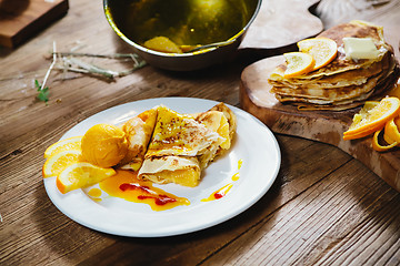 Image showing stuffed pancakes with orange syrup and ice-cream