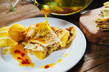 Image showing stuffed pancakes with orange syrup and ice-cream