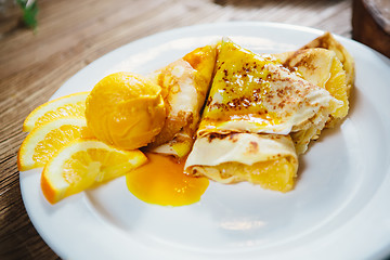 Image showing stuffed pancakes with orange syrup and ice-cream