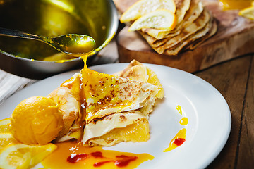 Image showing stuffed pancakes with orange syrup and ice-cream